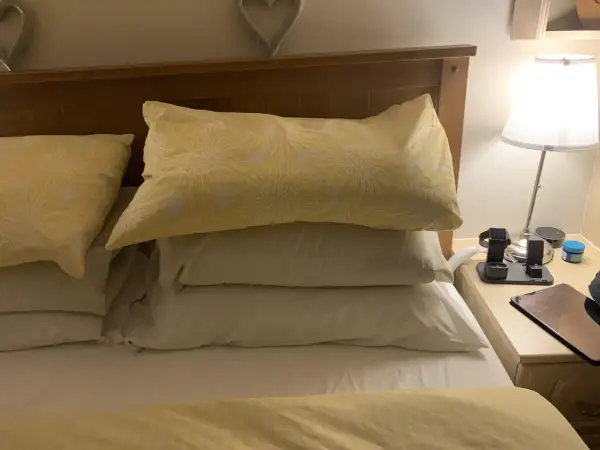 A stack of three pillows, one with a yellow sunflower pattern, sits on a bed. Perfect for sleeping with 3 pillows for ultimate comfort.